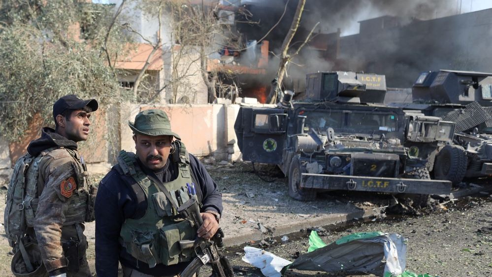 Iraqi special forces soldiers stand in front of humvees destroyed by an Islamic State suicide car bomb attack during clashes in Mosul