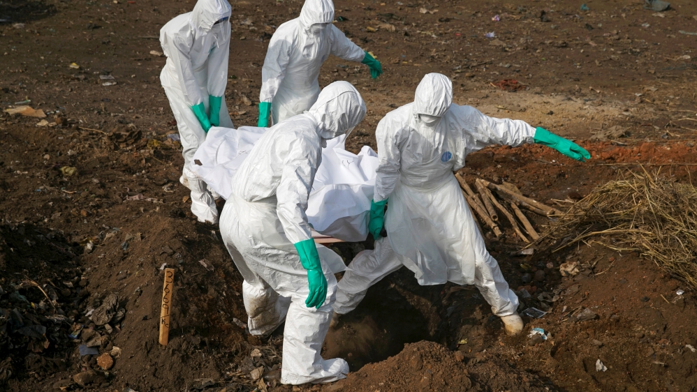 Health workers carry the body of a suspected Ebola victim for burial at a cemetery in Freetown