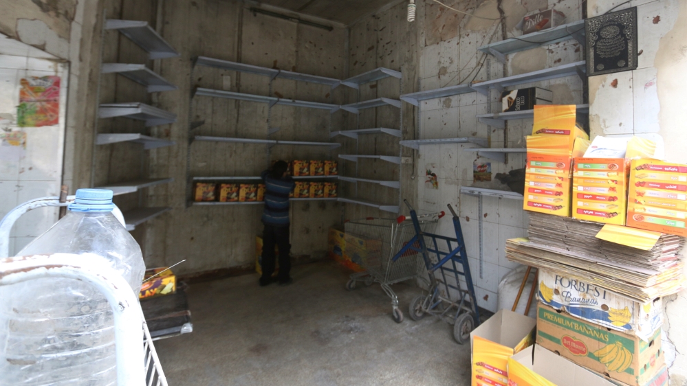 A boy inspects boxes inside a grocery shop with low supplies in the rebel-held besieged area of Aleppo