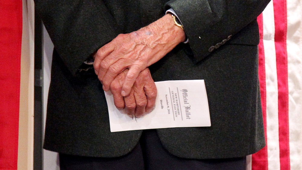 A voter holds onto his ballot as he waits to cast it in the U.S. presidential election at midnight in tiny Dixville Notch