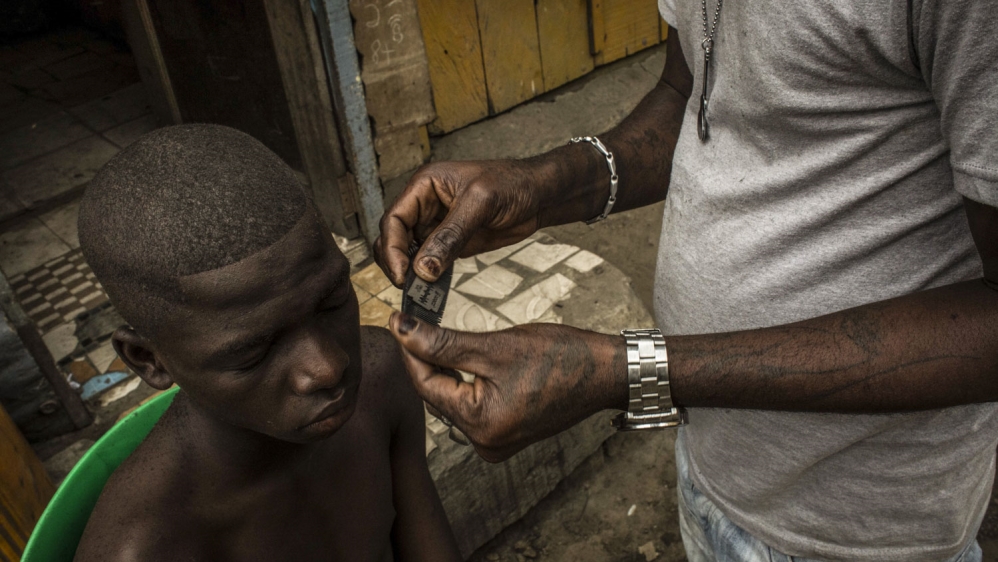  Kris Bitenda, with one of his clients at his barbershop, where he also draws tattoos, in the Lubugi district in Kinshasa [Francesca Volpi/Al Jazeera] 