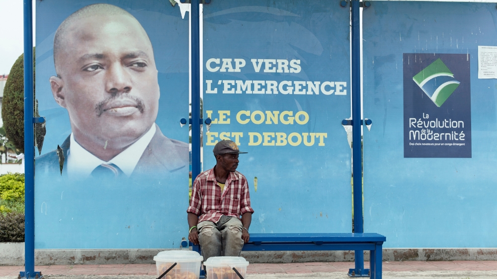 A vendor sits at a bus stand with pictures of Democratic Republic of Congo''s President Joseph Kabila in Kinshasa