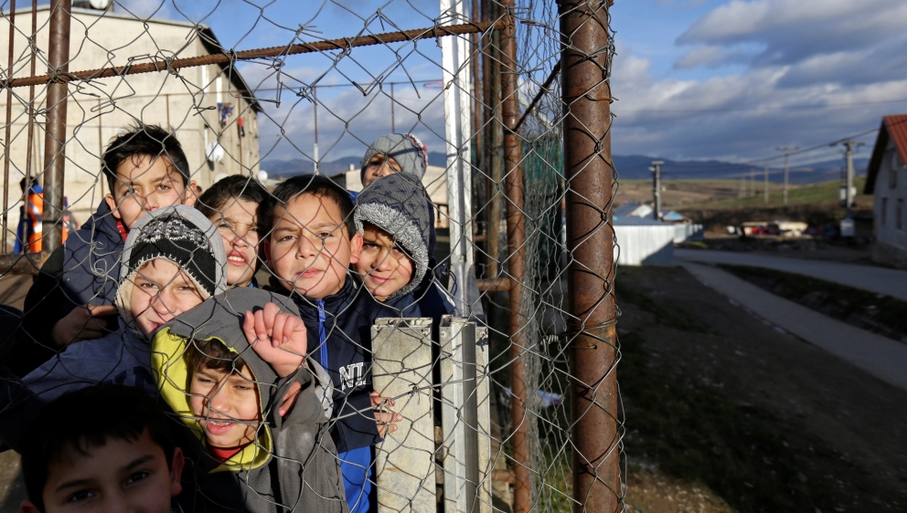 Roma children stand behind a fence near the so called "Sheffield Square" in the town of Bystrany
