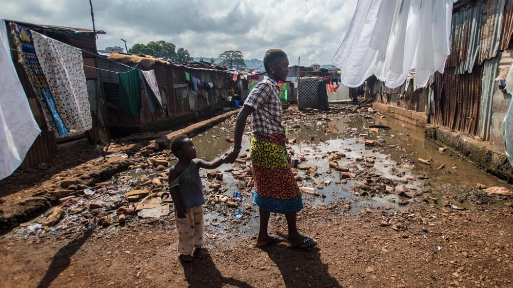 Aminatta and Thomas outside their house in Kroo Bay [ Olivia Acland/ Al Jazeera]