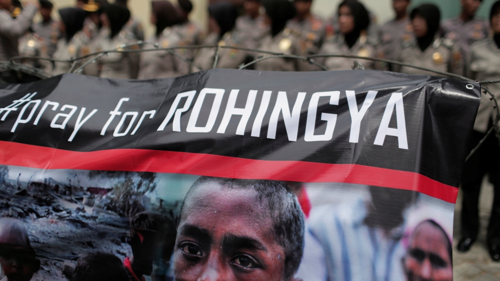 A banner is seen during a protest against what demonstrators say is the crackdown on ethnic Rohingya Muslims in Myanmar, as police stand guard in front of the Myanmar embassy in Jakarta