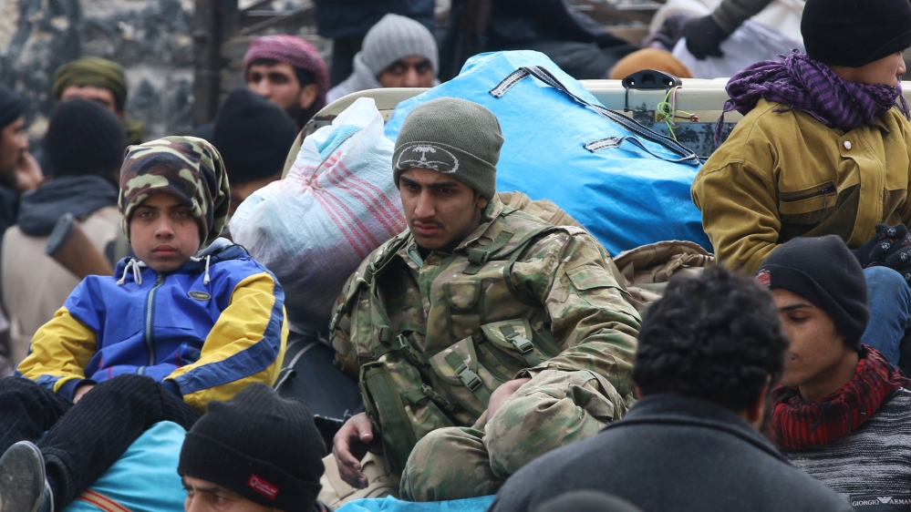 Rebel fighters and civilians gather as they wait to be evacuated from a rebel-held sector of eastern Aleppo