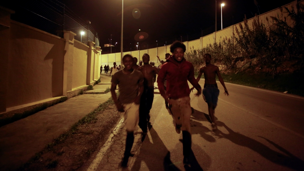 African migrants run on a road after crossing the border fence between Morocco and Spain''s north African enclave of Ceuta