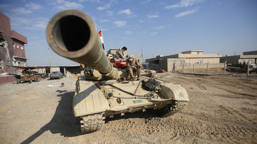 Iraqi army members sit on a tank during a battle with Islamic State militants in Talkeef district, north of Mosul