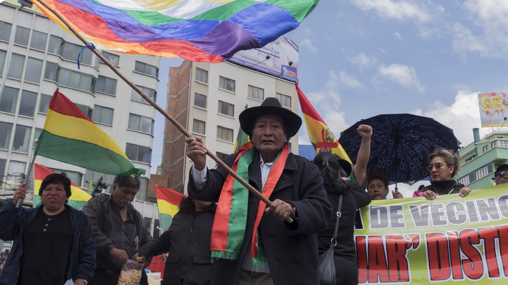 A man waves a Wiphala flag, which is a symbol for the indigenous tribes [Eline van Nes/Al Jazeera]