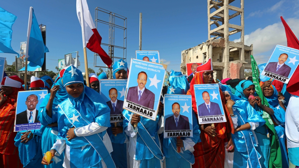 Women carry posters of the newly elected Somalian President Mohamed Abdullahi Mohamed as they celebrate his victory, near the Daljirka Dahson monument in Mogadishu