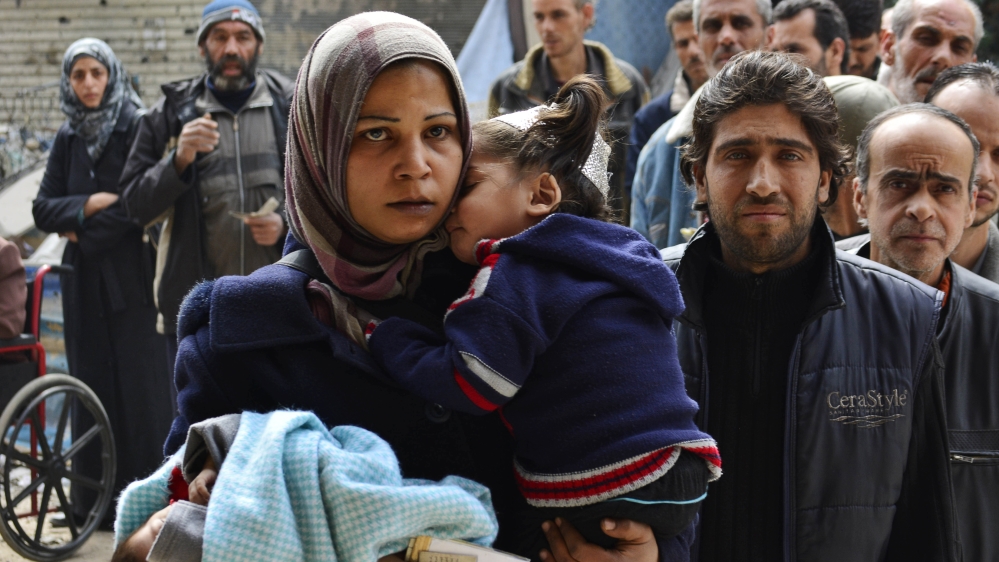 Syrians queue for food at the at the Palestinian refugee camp of Yarmouk