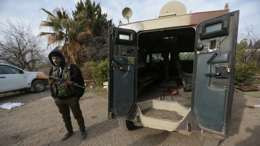 A rebel fighter stands with his weapon near a military vehicle on the outskirts of the northern Syrian town of al-Bab