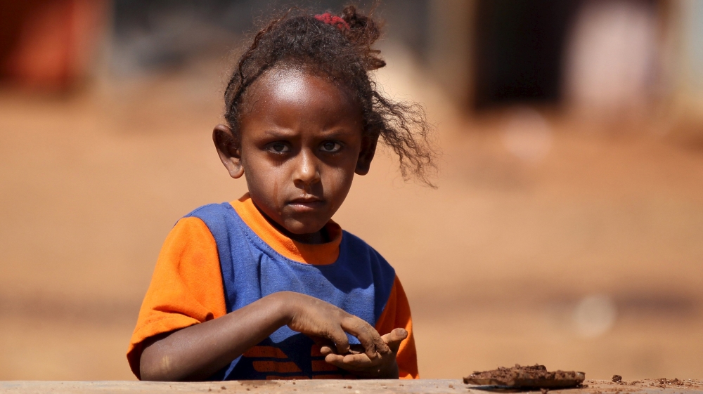 An Eritrean refugee girl plays with clay in front of their shelter in Mai-Aini refugee camp near the Eritrean boarder in the Tigrai region in Ethiopia