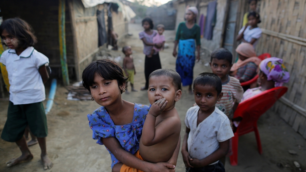A Rohingya refugee girl carries a baby inside a refugee camp in Sitwe, Rakhine state