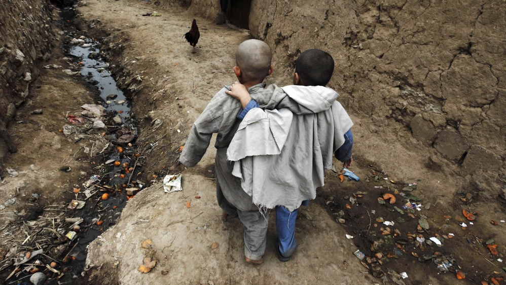 Boys walk down an alley at a slum on the outskirts of Islamabad