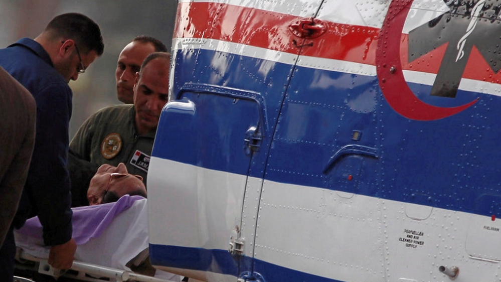 Former Egyptian President Hosni Mubarak lies on a stretcher while being transported ahead of his trial in Cairo