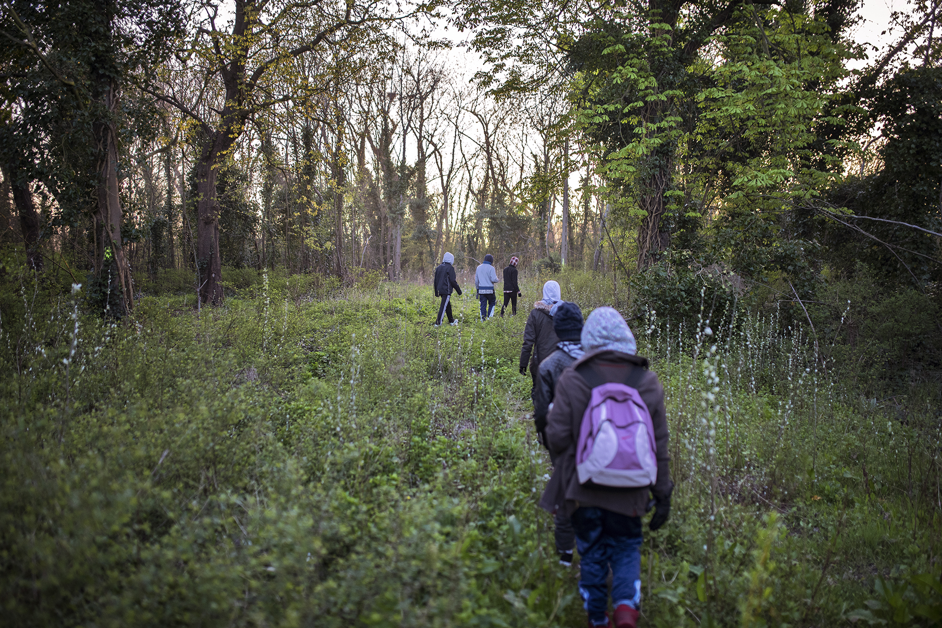 Badessa, Negasu and Feyissa leave the bunker and make their way from the forest towards the mobile distribution point to eat in Calais [Guillem Trius/Al Jazeera]