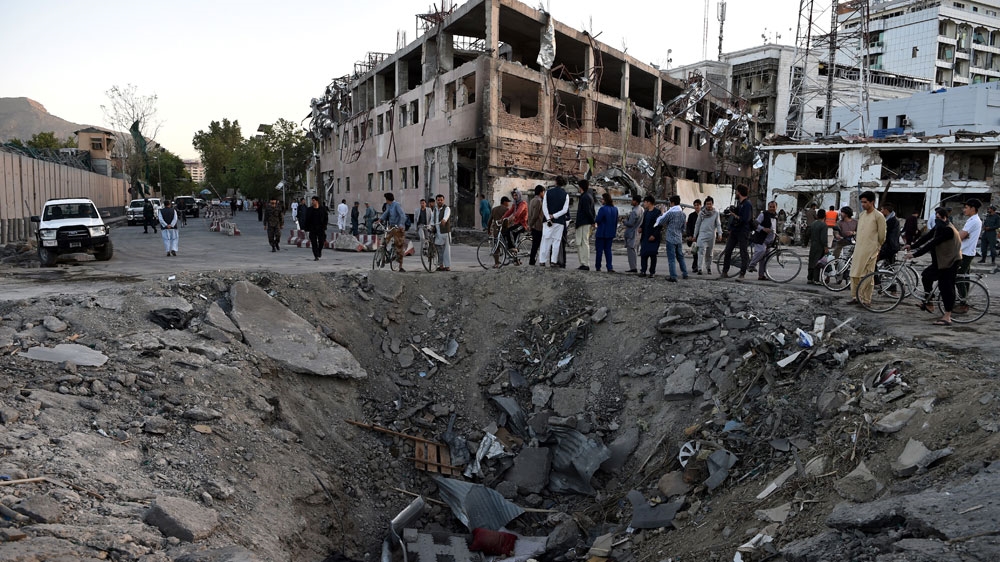 Afghan security forces and residents stand near the crater left by the truck bomb attack in Kabul [Wakil Kohsar/AFP]