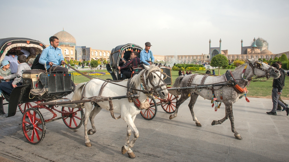 Tourists ride horse-drawn carriages through Naqshe Jahan Square [Wojtek Arciszewski/Al Jazeera]