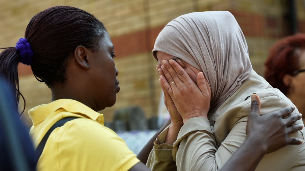 Women comfort each other near the Grenfell apartment tower block in North Kensington, London