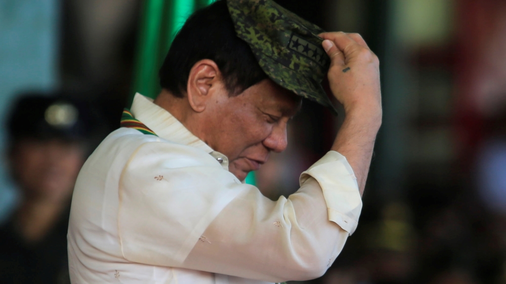 Philippine President Rodrigo Duterte tries on a military hat given to him during the 120th founding anniversary of the Philippine Army (PA) at Taguig city, metro Manila
