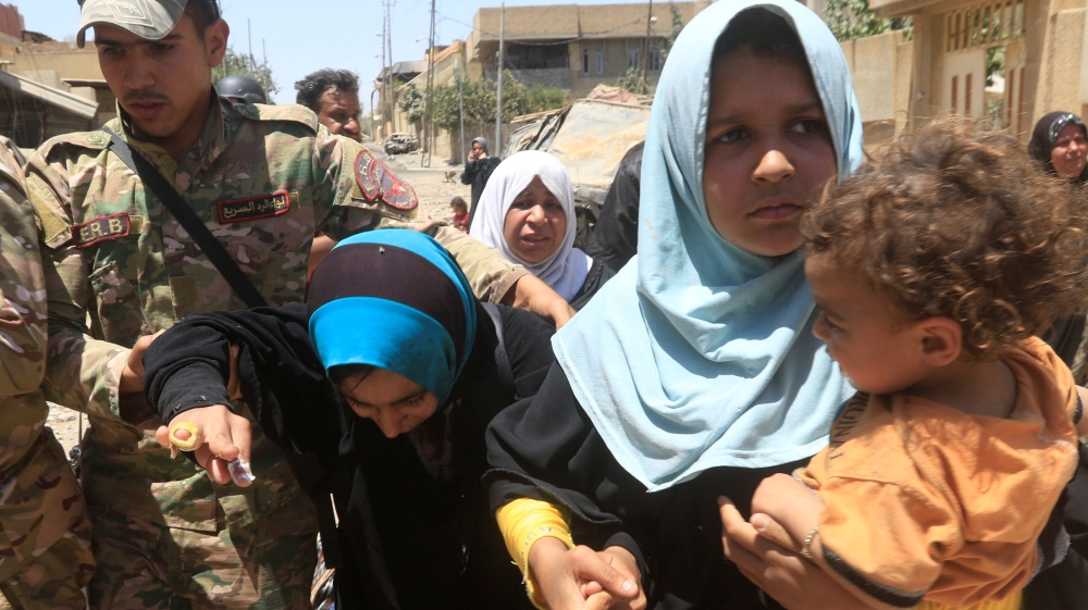 Iraqi forces help women who fled their homes during a fight in Mosul's Zanjili neighbourhood [Alaa Al-Marjani/Reuters]