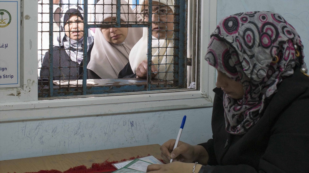 Gaza City residents queue for food aid vouchers at the UNRWA distribution warehouse [William Parry/Al Jazeera]