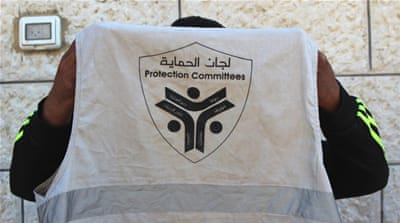Mohammad Shihada holds up his neighbourhood watch vest [Jaclynn Ashly/Al Jazeera]
