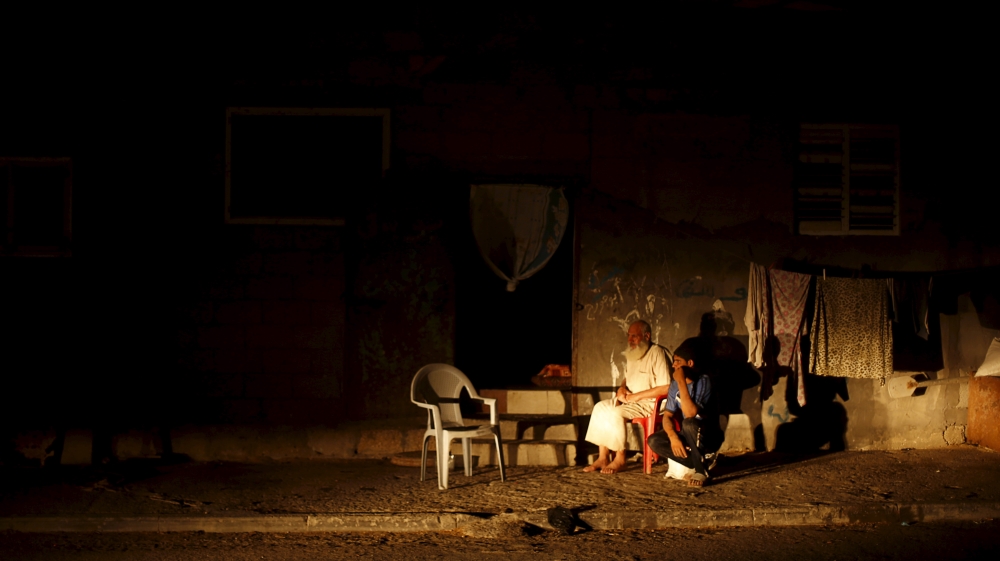Palestinians sit outside their house as they flee the heat during power cut at Shatti (beach) refugee camp in Gaza City