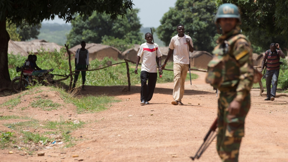 Members of the of the Anti-Balaka armed militia walk next to a United Nations peacekeeping soldier in the village of Makunzi Wali