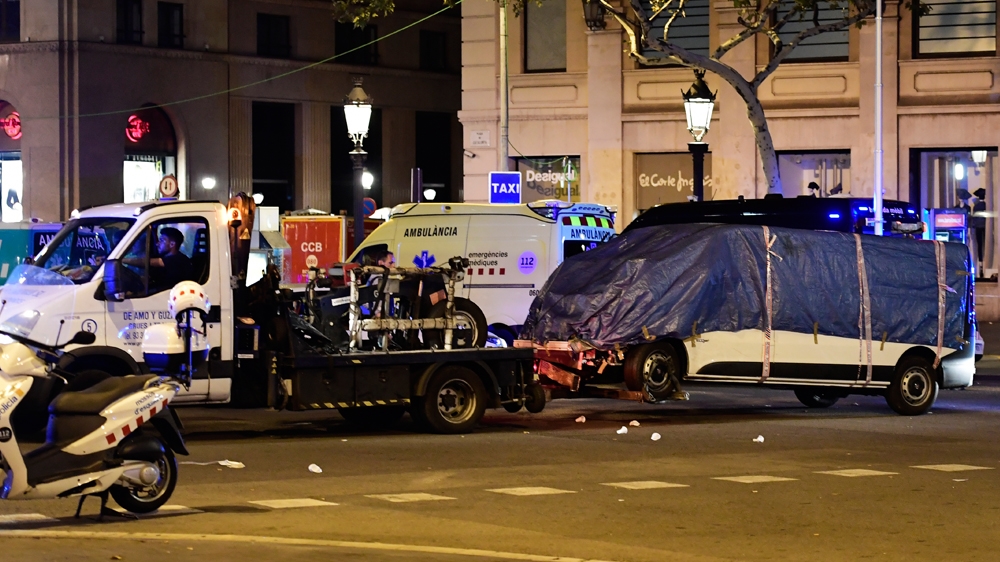 The van that ploughed into the crowd, killing at least 13 people and injuring 120 others, is towed away [Josep Lago/AFP]
