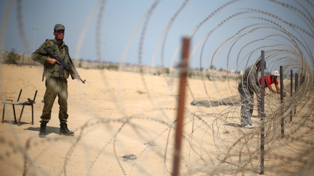 A member of the Palestinian security forces, loyal to Hamas, stands guard as men set up a barbed wire on the border with Egypt, in Rafah in the southern Gaza Strip