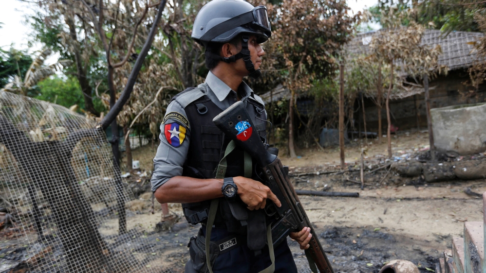 Police officer guards near a house which was burnt down during the last days of violence in Maungdaw
