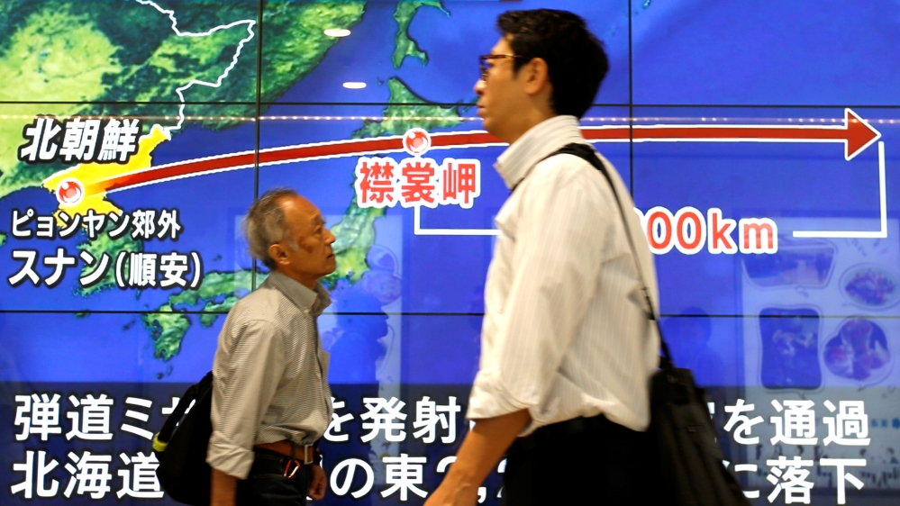 Passersby in Tokyo walk in front of a TV screen reporting news about North Korea''s missile launch
