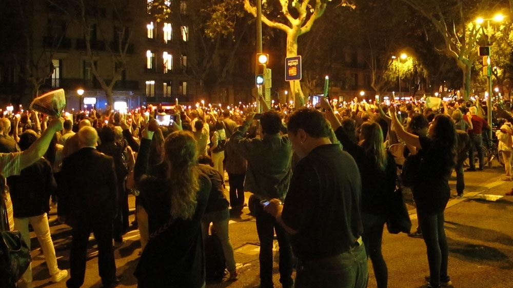 Protesters raise their candles in the air as a police helicopter passes [Creede Newton/Al Jazeera] 