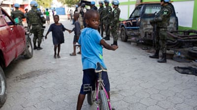 Children play in the street while UN peacekeepers from Brazil patrol in Port-au-Prince [File: Dieu Nalio Chery/AP Photo] 