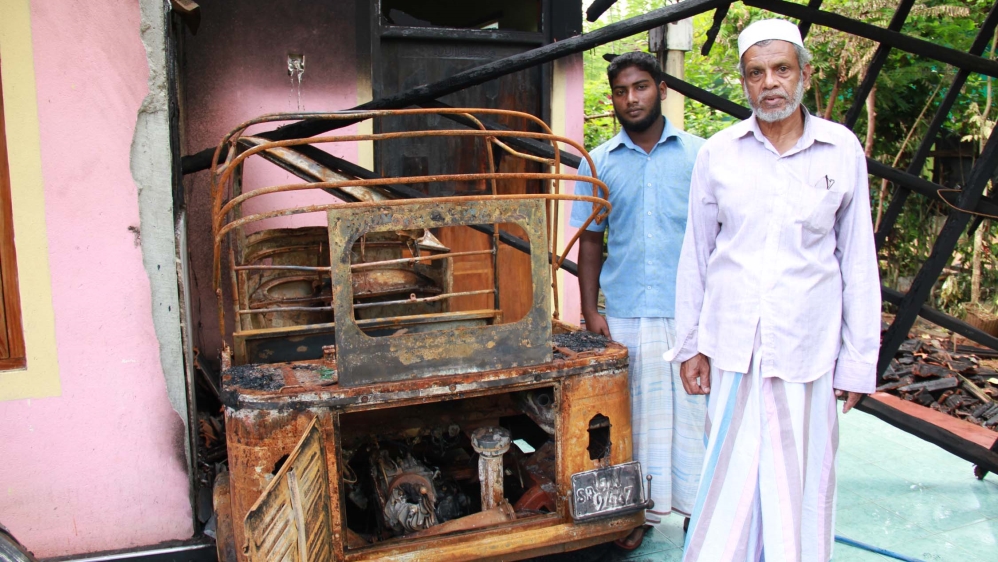 'They smashed our gate and came in and poured petrol on my tuk-tuk and set it on fire,' said Muhammad Abrar, pictured with his son [M Riza/Al Jazeera]