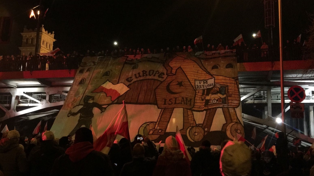 A banner depicting a refugee as a suicide bomber on board a trojan horse [Agnieszka Pikulicka-Wilczewska/Al Jazeera]