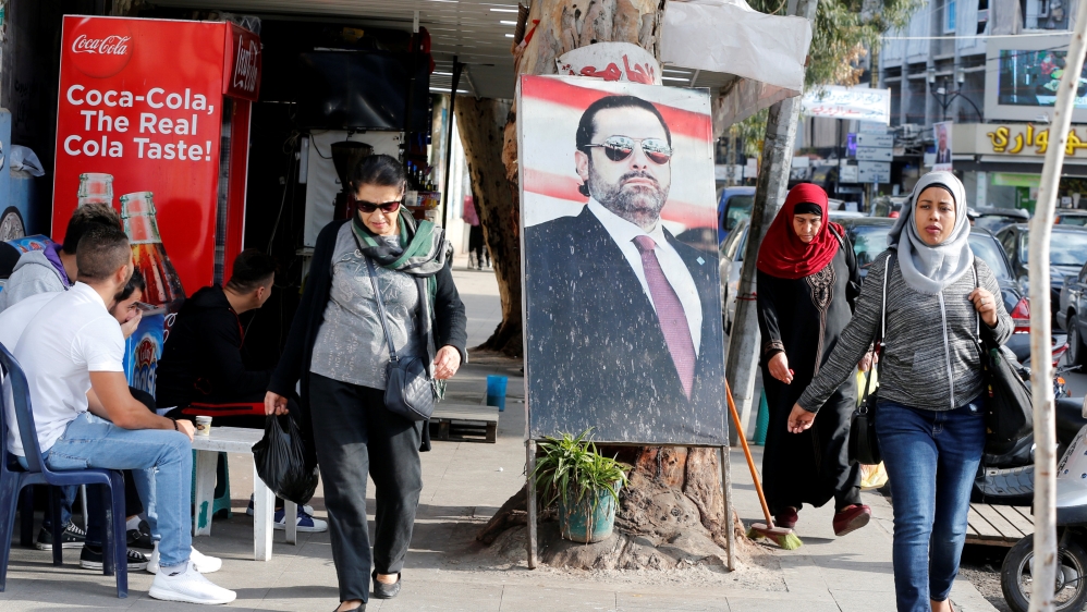 People walk next to a poster depicting Lebanon''s Prime Minister Saad al-Hariri, who has resigned from his post, along a street in the mainly Sunni Beirut neighbourhood of Tariq al-Jadideh in Beirut