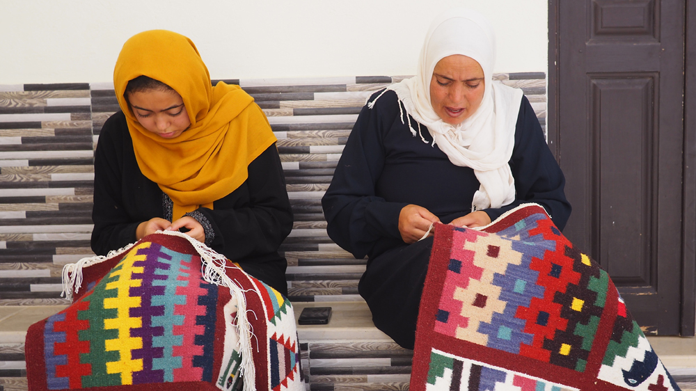 Sarah Bouzayene, Sihem's oldest daughter, helps her mother with designs [Al Jazeera]