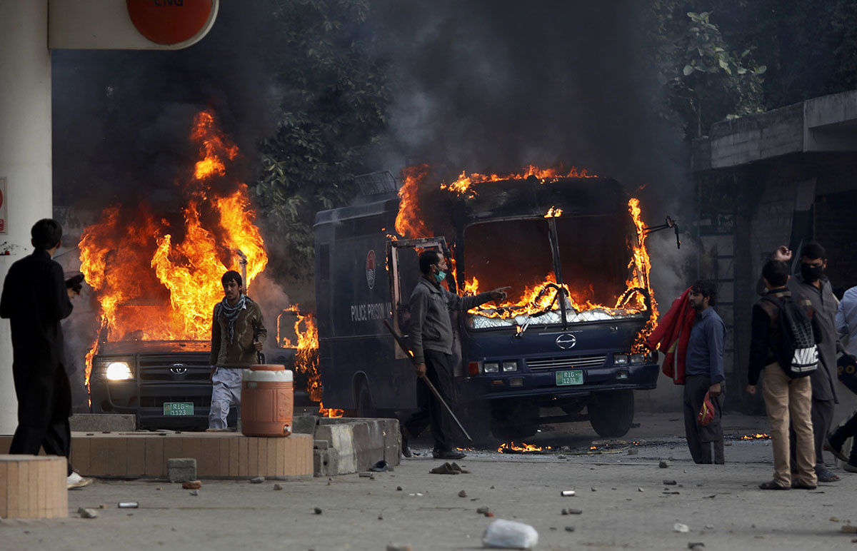 Pakistani protesters gather next to burning police vehicles after setting on fire them during a clash in Islamabad, Pakistan, Saturday, Nov. 25, 2017. Pakistani police have launched an operation to cl
