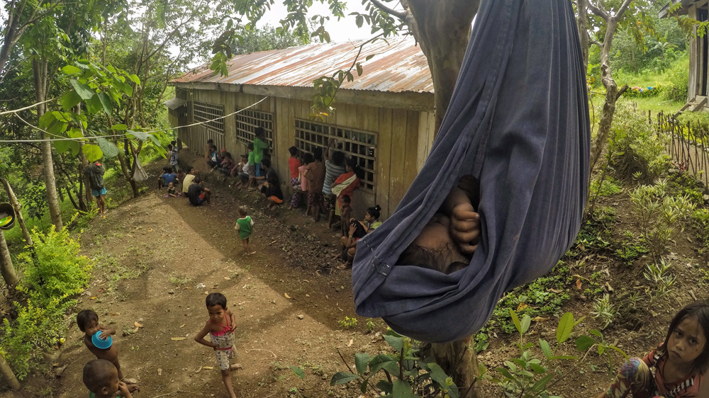 A child sleeps in a makeshift hammock outside the school [Mick Basa/Al Jazeera]
