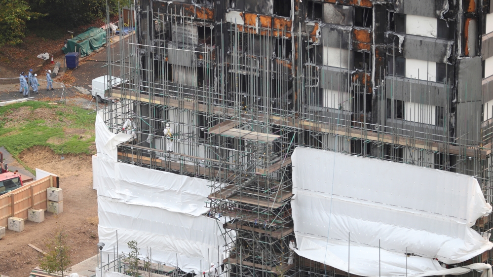 Workers erect scaffolding around the Grenfell Tower in October [Hannah Mckay/Reuters]
