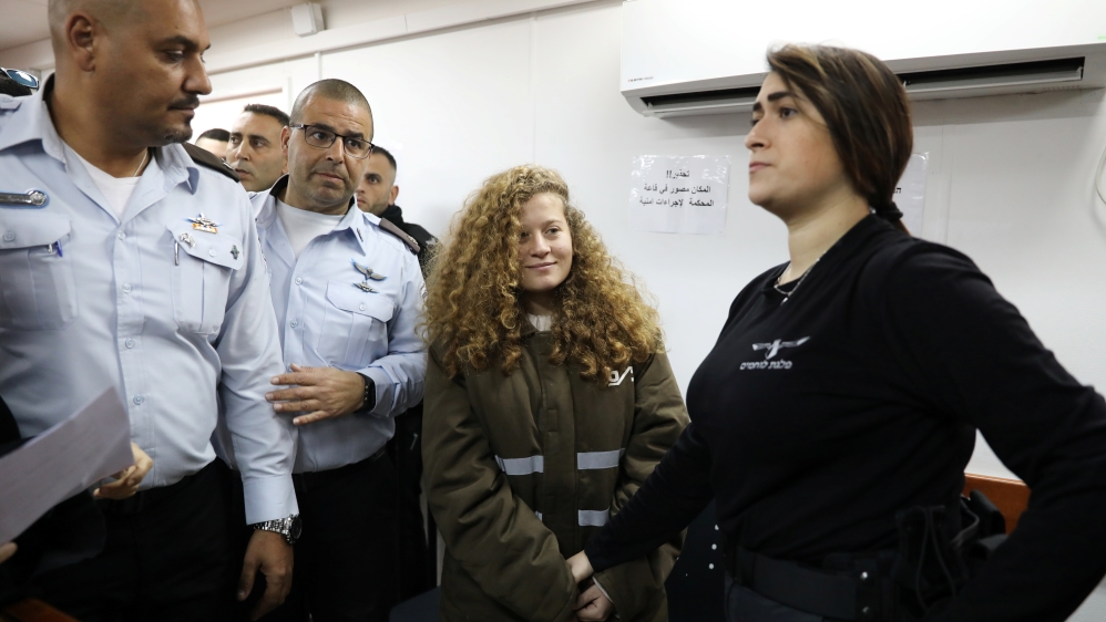 Palestinian teen Ahed Tamimi enters a military courtroom escorted by Israeli security personnel at Ofer Prison, near the West Bank city of Ramallah