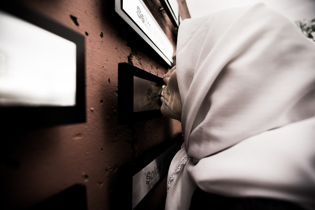 Kosovar woman kisses a plate on the Wall of the Memory. Her husband and her sons were killed during the war, Gjacova.