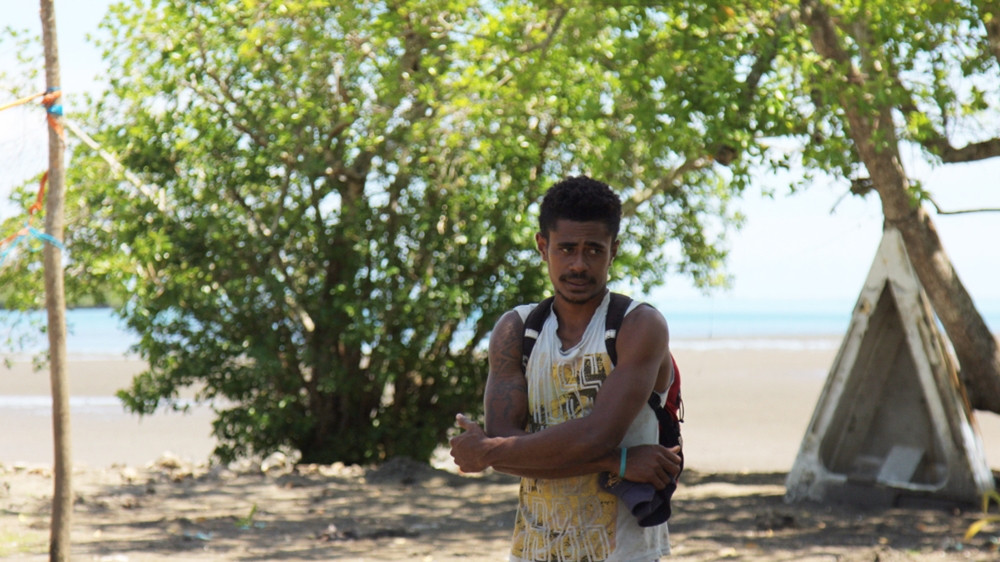 The tree behind Lorima Bulimaitoga used to sit in the grass, but the shoreline changed [Loes Witschge/Al Jazeera]