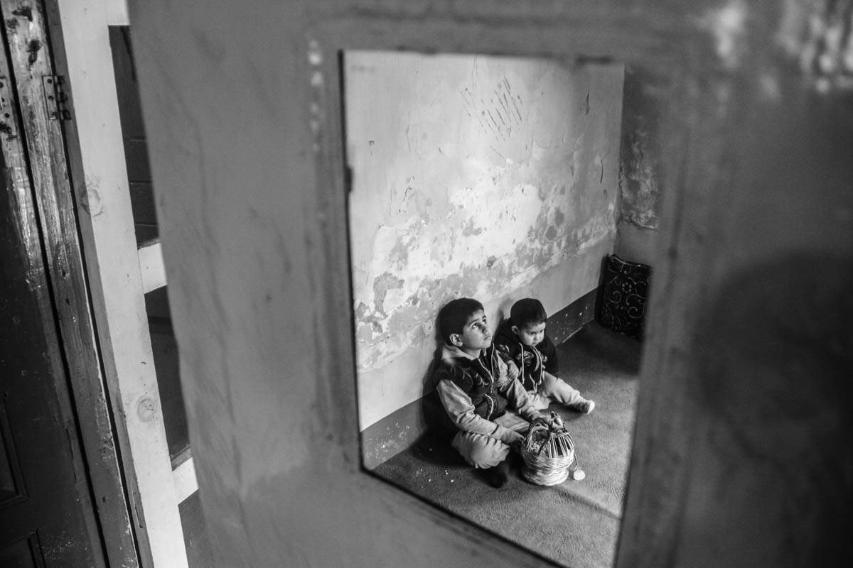 Suhaib and Iffaq sitting inside living room of their house warming hands on a fire pot. Their father was killed on July 9 in village Akad of Anantnag, about 62 km south of Srinagar city, the summer ca