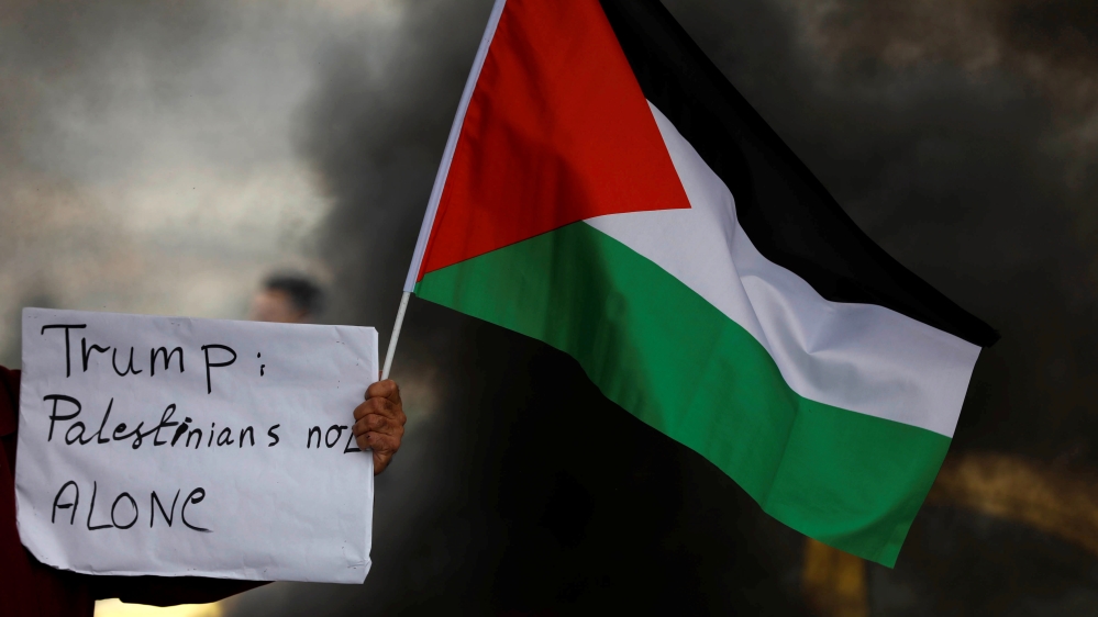A demonstrator holds a sign and a Palestinian flag at a protest against Trump''s decision to recognise Jerusalem as the capital of Israel, near the West Bank city of Nablus [File: Mohamad Torokman/Reu