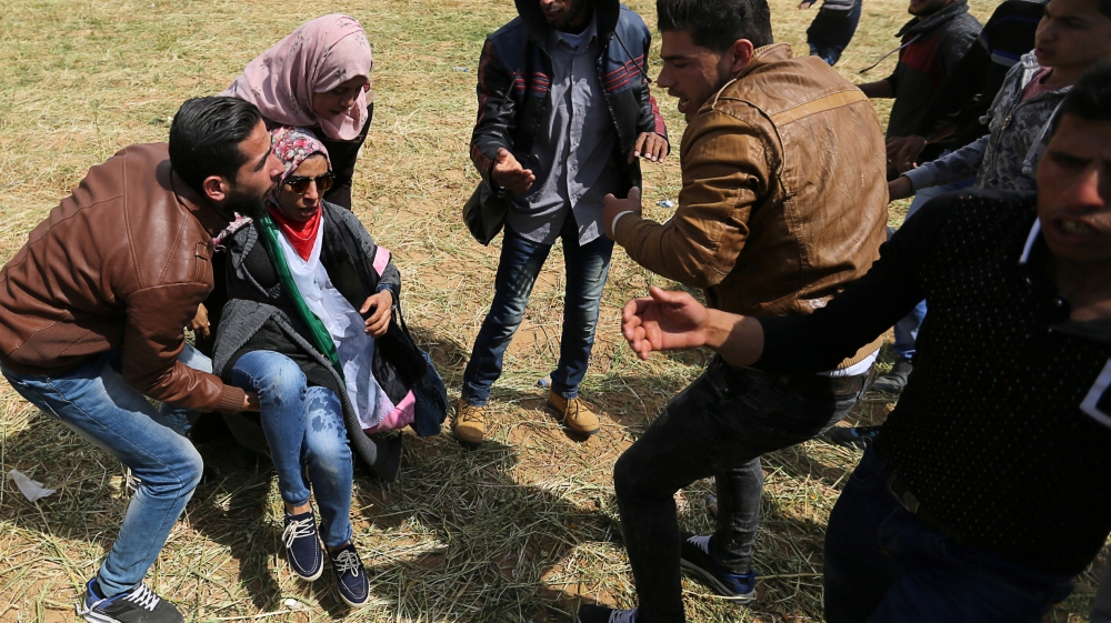 A wounded Palestinian woman is evacuated during clashes with Israeli troops, during a tent city protest along the Israel border with Gaza