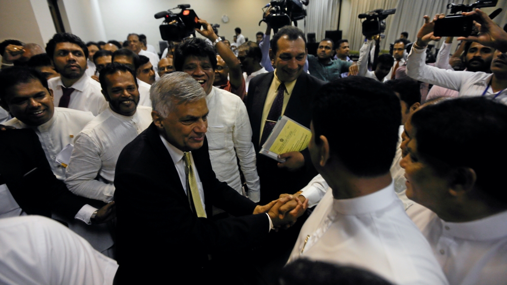 Sri Lankan Prime Minister Wickremesinghe shakes hands with his party members who supported him after he survived a no confidence vote in the parliament in Colombo